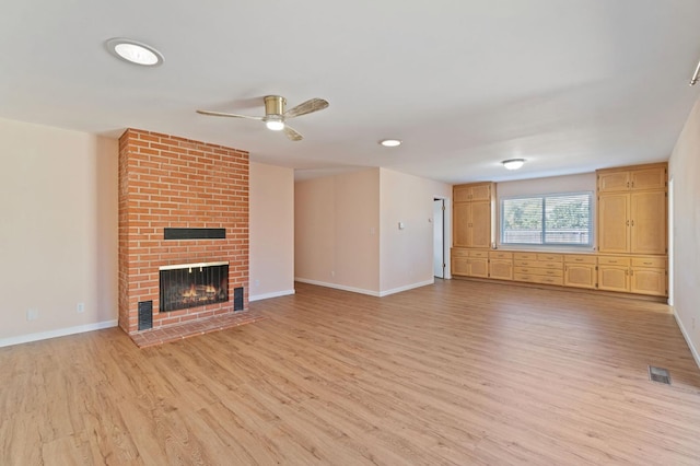 unfurnished living room featuring ceiling fan, light hardwood / wood-style floors, and a brick fireplace