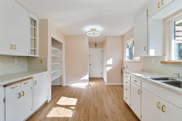 kitchen featuring decorative backsplash, light hardwood / wood-style flooring, and white cabinetry