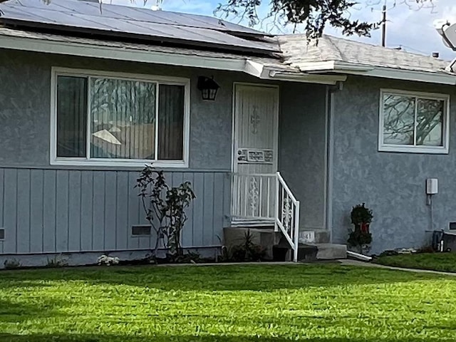 doorway to property with solar panels and a yard