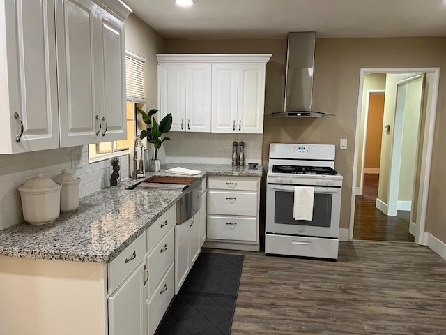 kitchen with white cabinets, light stone counters, white gas range oven, dark wood-type flooring, and wall chimney range hood