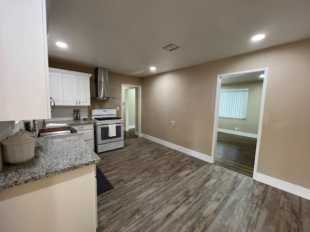 kitchen with dark wood-type flooring, wall chimney exhaust hood, white gas stove, white cabinetry, and light stone counters