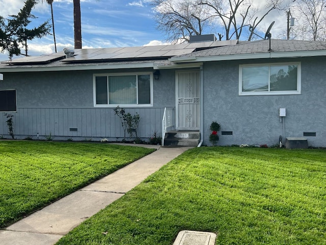 ranch-style house with solar panels and a front lawn