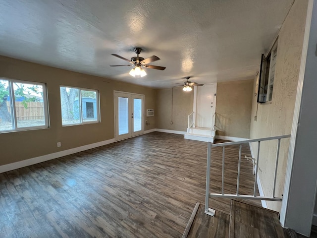 unfurnished living room featuring french doors, dark hardwood / wood-style flooring, and a textured ceiling