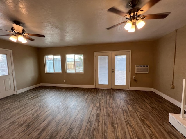 empty room featuring dark hardwood / wood-style floors, a wall mounted AC, a textured ceiling, and french doors