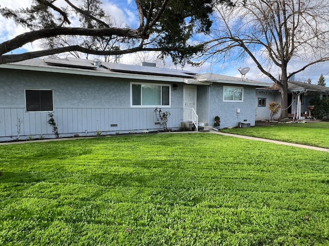 ranch-style house featuring solar panels and a front lawn