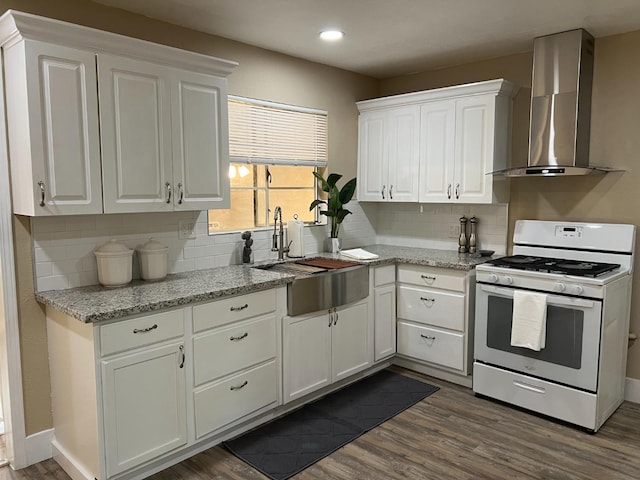 kitchen with sink, white range with gas stovetop, white cabinets, and wall chimney exhaust hood