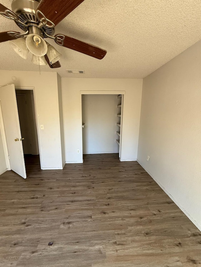 unfurnished bedroom with a textured ceiling, a closet, wood-type flooring, and ceiling fan