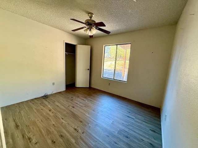 unfurnished bedroom featuring ceiling fan, a closet, a textured ceiling, and light hardwood / wood-style flooring