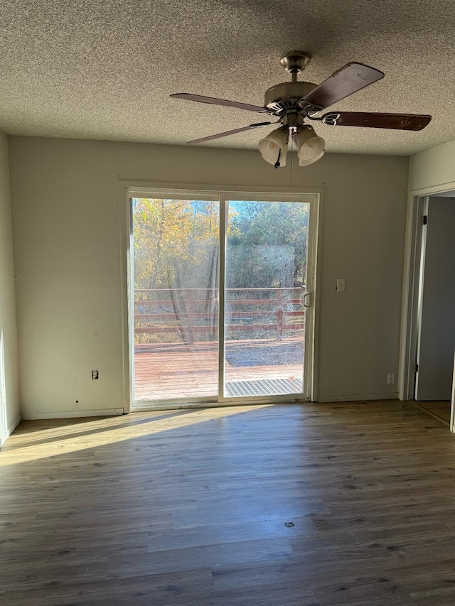 empty room featuring a textured ceiling, ceiling fan, a wealth of natural light, and wood-type flooring