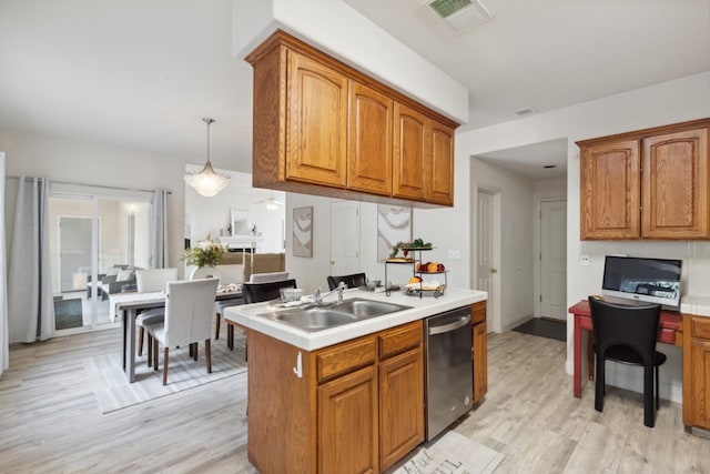 kitchen with sink, light hardwood / wood-style flooring, stainless steel dishwasher, pendant lighting, and a kitchen island with sink