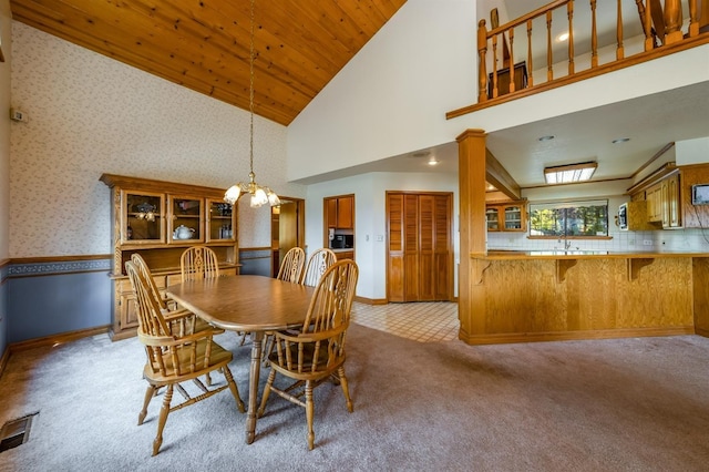 carpeted dining room with a chandelier, high vaulted ceiling, and sink