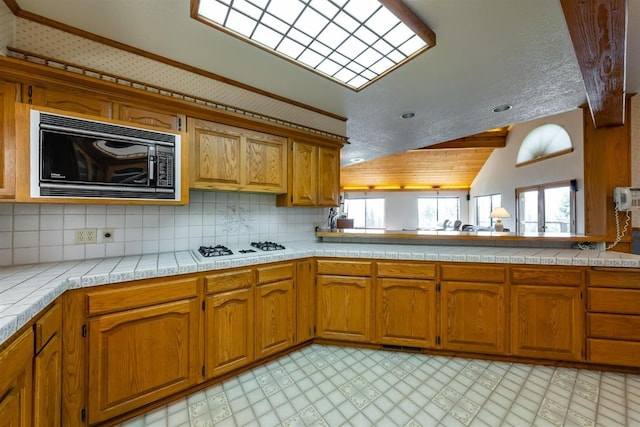 52180 Chahlip Ln, Shaver Lake, CA 93664 - kitchen featuring black microwave, lofted ceiling, brown cabinets, decorative backsplash, and light floors