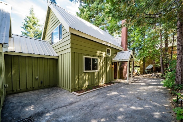 view of side of property with metal roof, board and batten siding, and a chimney