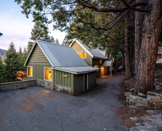 chalet / cabin with metal roof, board and batten siding, and stone siding