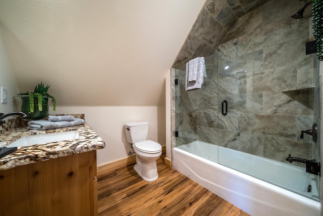 bathroom with lofted ceiling, toilet, combined bath / shower with glass door, wood finished floors, and baseboards