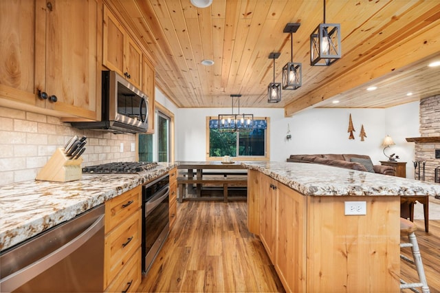 kitchen featuring a center island, light wood finished floors, backsplash, appliances with stainless steel finishes, and open floor plan