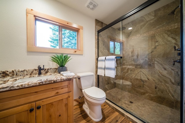 bathroom featuring toilet, wood finished floors, visible vents, vanity, and a shower stall