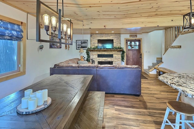 living area with stairs, a stone fireplace, wood finished floors, and wood ceiling