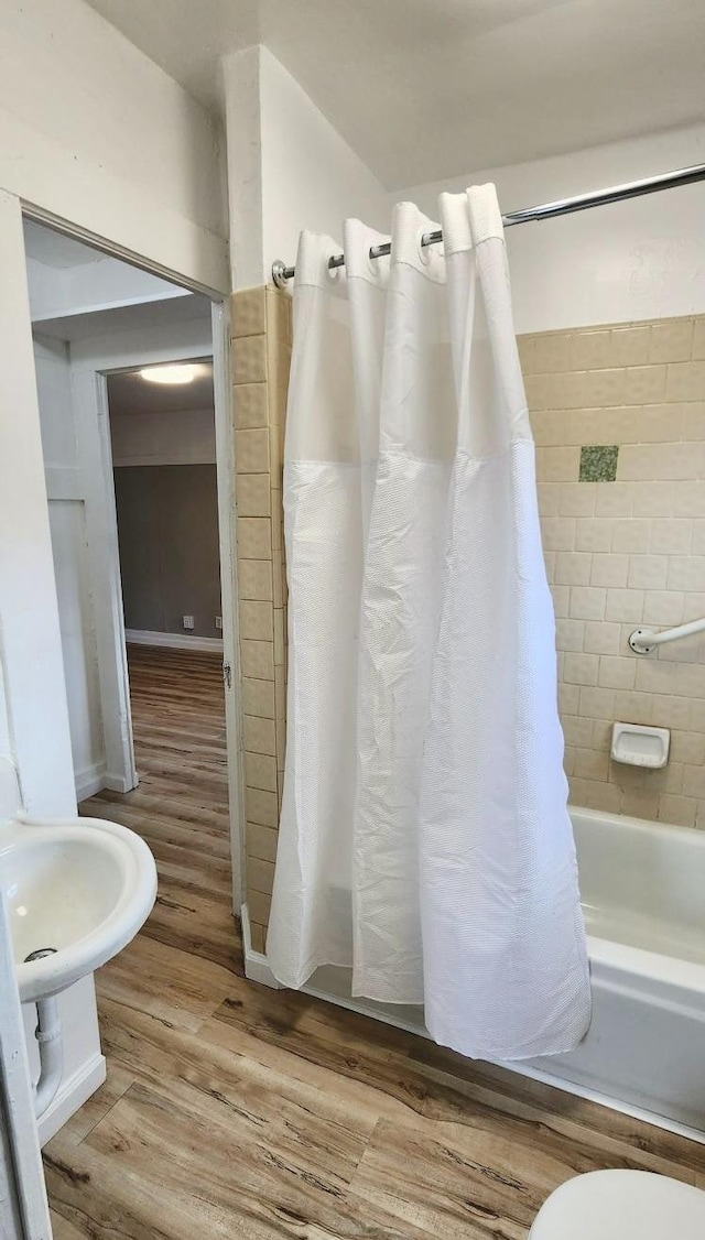 bathroom with shower / bath combination with curtain, wood-type flooring, and toilet