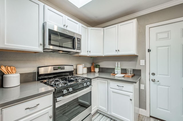 kitchen featuring white cabinetry, appliances with stainless steel finishes, and crown molding