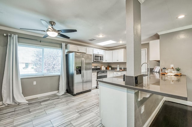 kitchen featuring appliances with stainless steel finishes, white cabinetry, ornamental molding, ceiling fan, and kitchen peninsula