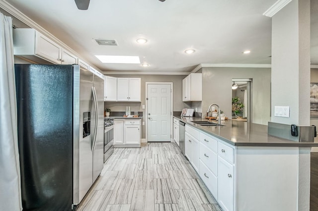 kitchen with sink, a skylight, kitchen peninsula, stainless steel appliances, and white cabinets