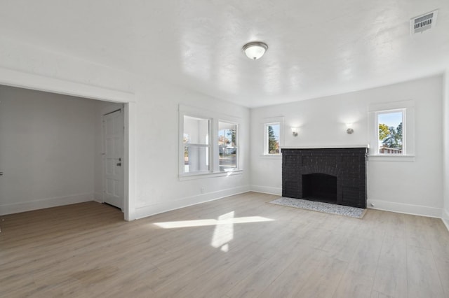 unfurnished living room with plenty of natural light, light hardwood / wood-style floors, and a fireplace