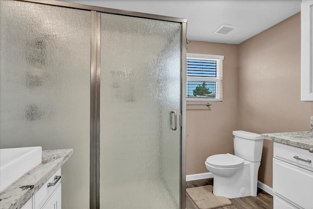 bathroom featuring vanity, hardwood / wood-style flooring, toilet, and a shower with door