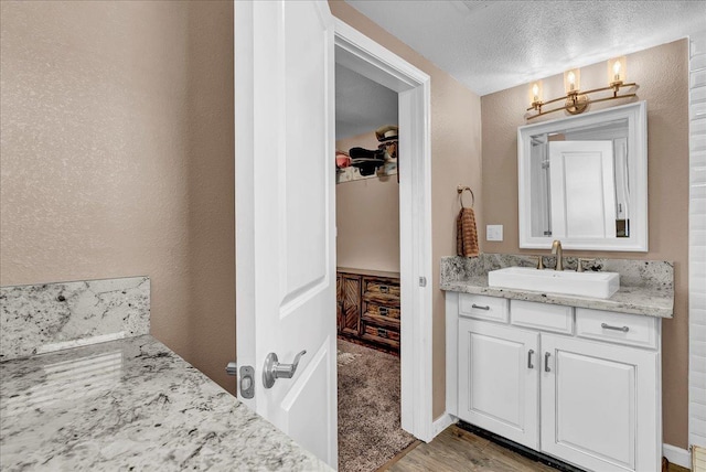 bathroom with hardwood / wood-style floors, vanity, and a textured ceiling