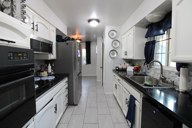 kitchen with tasteful backsplash, white cabinets, dark countertops, black appliances, and a sink