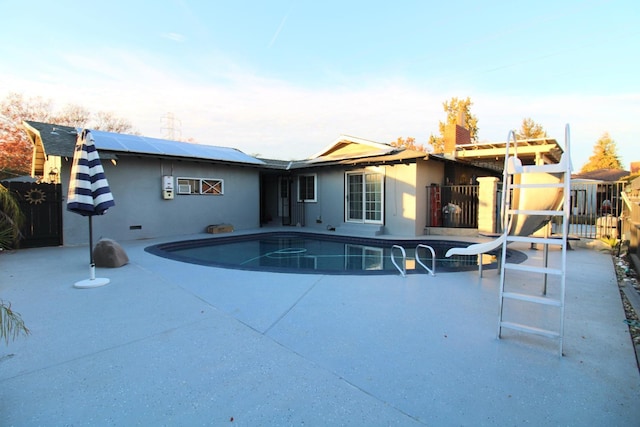 rear view of property with solar panels, a patio area, fence, and a fenced in pool