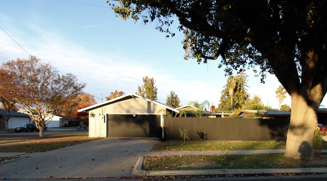 view of side of home with a garage, driveway, and fence