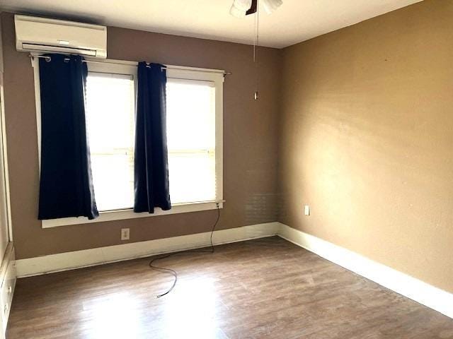 spare room featuring wood-type flooring and a wall unit AC