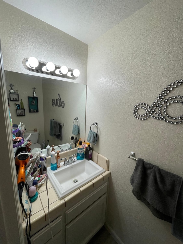 bathroom with vanity, a textured ceiling, and toilet