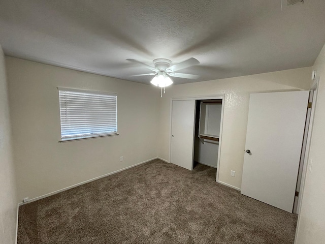 unfurnished bedroom featuring dark colored carpet, ceiling fan, a textured ceiling, and a closet