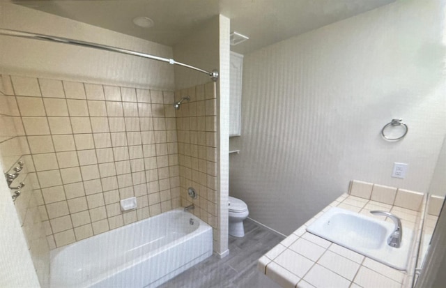 full bathroom with tiled shower / bath combo, hardwood / wood-style flooring, toilet, and sink