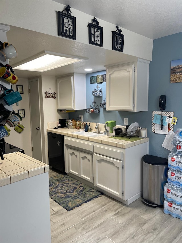 kitchen with tile counters, white cabinets, and light hardwood / wood-style floors