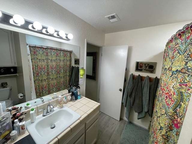 bathroom with hardwood / wood-style floors, vanity, a textured ceiling, and toilet