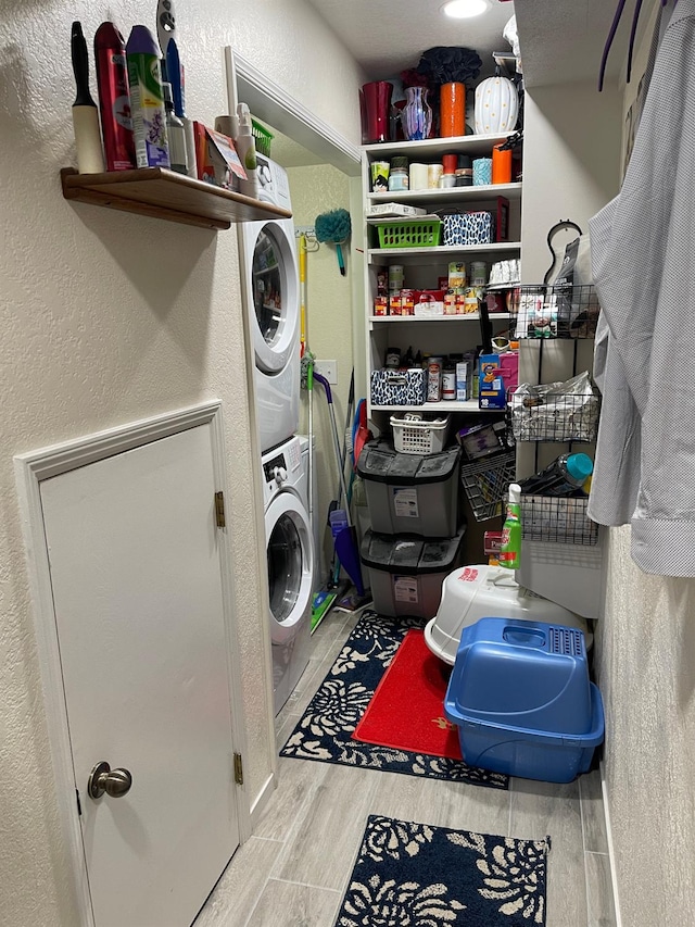 laundry area with hardwood / wood-style floors and stacked washer and clothes dryer