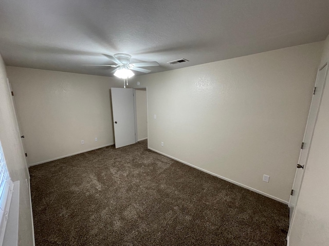 unfurnished bedroom featuring a textured ceiling, dark carpet, and ceiling fan