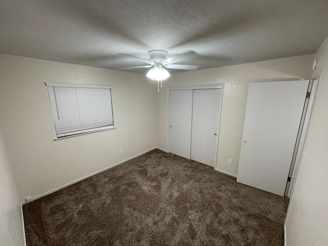 unfurnished bedroom with ceiling fan, a closet, dark carpet, and a textured ceiling