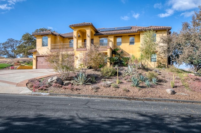 mediterranean / spanish-style home with solar panels, a garage, and a balcony