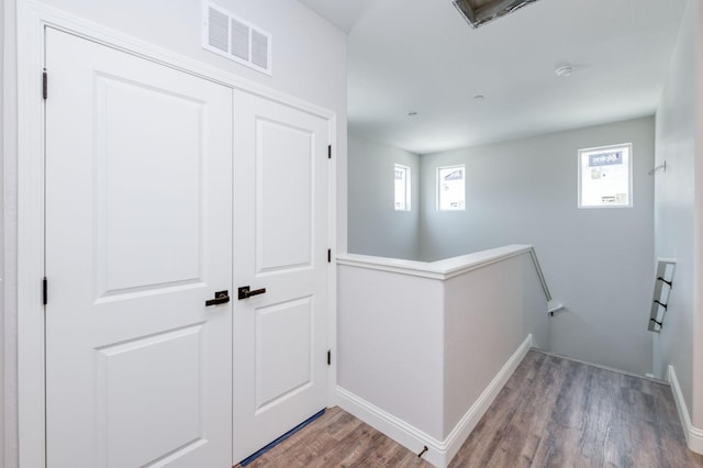 hall with a wealth of natural light and hardwood / wood-style floors