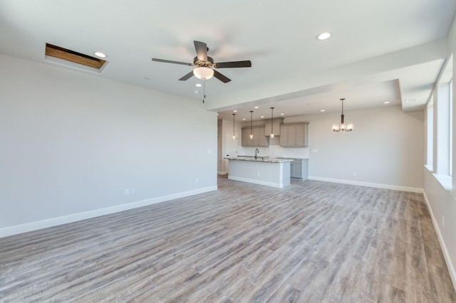 unfurnished living room with ceiling fan, sink, and light hardwood / wood-style flooring