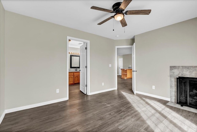 unfurnished living room with ceiling fan, a fireplace, dark wood-type flooring, and sink