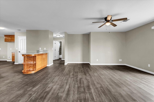 unfurnished living room with ceiling fan and dark wood-type flooring