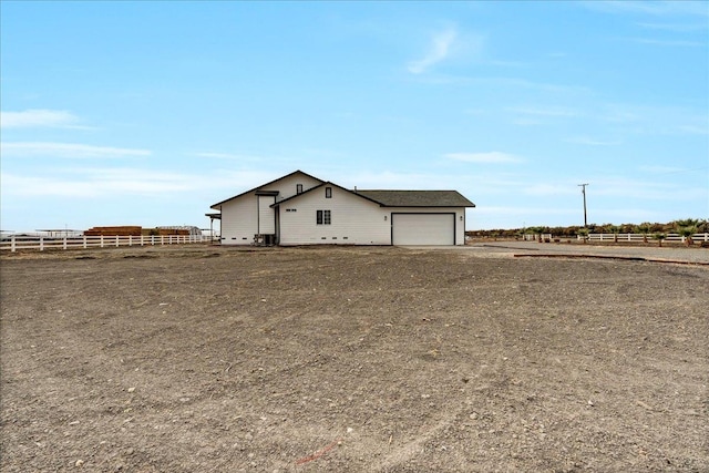 view of front of home with a rural view and a garage