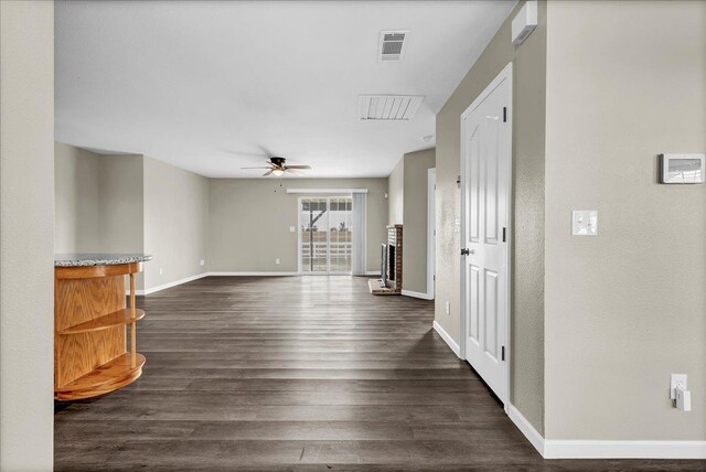 interior space featuring a brick fireplace, ceiling fan, and dark wood-type flooring