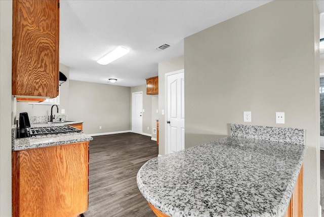 kitchen featuring light stone countertops, kitchen peninsula, sink, range, and dark hardwood / wood-style floors