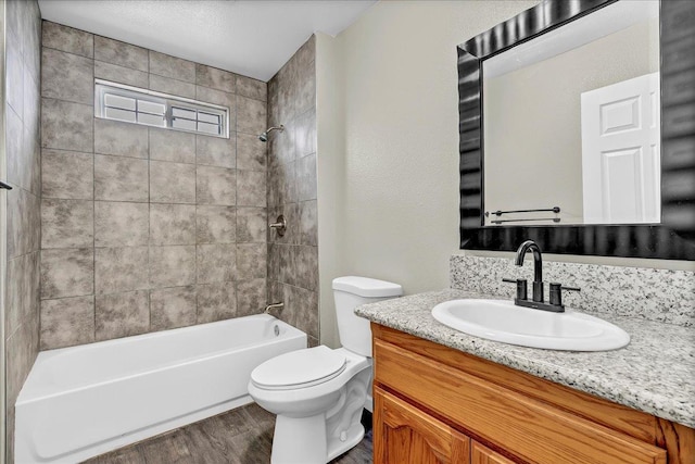 full bathroom with vanity, wood-type flooring, tiled shower / bath combo, and toilet